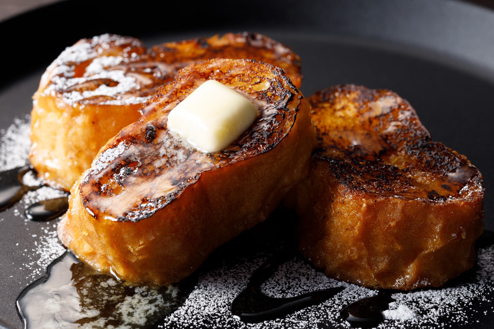 黒い皿でバターが溶けているフレンチトースト